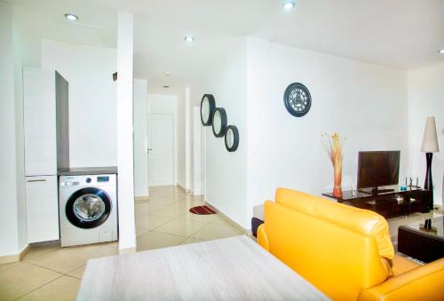 uma sala de estar com um sofá amarelo e uma máquina de lavar roupa em Adrich Properties Gallery em Acra