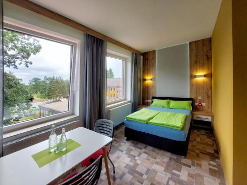 a bedroom with a bed and a table and a window at Wesendorf Residenz Premium Lounge in Wesendorf