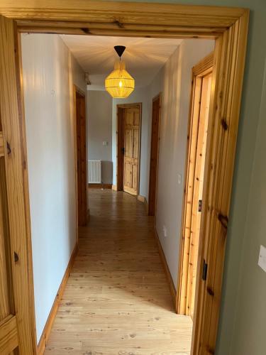 a hallway with a wooden floor and a chandelier at Cúlú in Kincasslagh