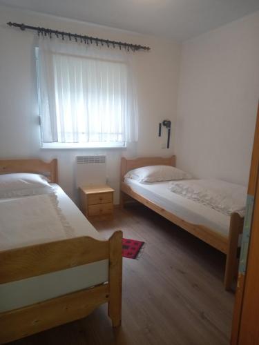 1 Schlafzimmer mit 2 Betten und einem Fenster mit einem Fenstervorhang in der Unterkunft Apartment Reni in Sarajevo