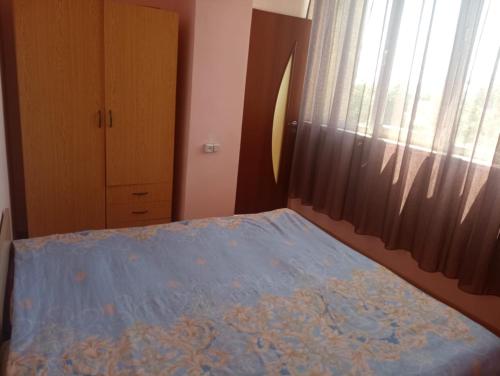 a bedroom with a bed with a blue blanket and a window at City Center Cozy Apartment Tigran Mets in Yerevan