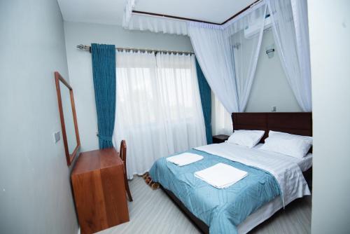 Lubowa View Apartments في كامبالا: غرفة نوم بسرير وطاولة ومرآة