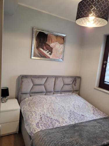 ein Bett in einem Schlafzimmer mit einem Bild an der Wand in der Unterkunft Apartament Chmielna - Waterlane Island in Danzig