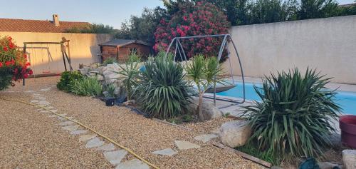 een achtertuin met een zwembad met planten en een schommel bij POOL HOUSE AVEC PISCINE ET SPA - RESIDENCE PRIVEE in Milhaud