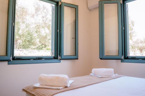 una camera da letto con due finestre e asciugamani su un letto di Abuelita Cottage a Andipáta Erísou