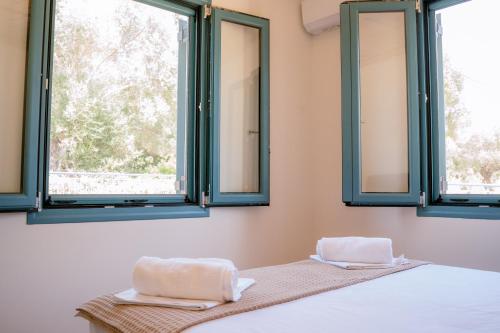 a bedroom with two windows with towels on a bed at Abuelita Cottage in Andipáta Erísou