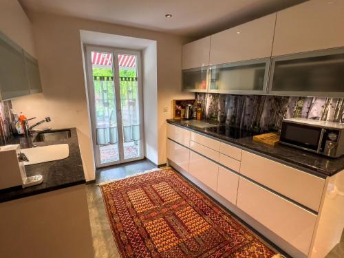 a kitchen with white cabinets and a kitchen rug at Ferienwohnung Waltensburg in Waltensburg