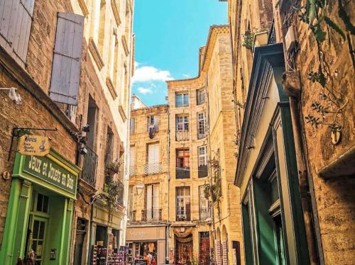 une rue étroite avec de grands immeubles dans une ville dans l'établissement Le Triplex Pézenas, à Pézenas