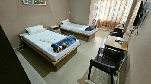 a room with two beds and a table and a chair at Hotel Rishiraj in Jorhāt