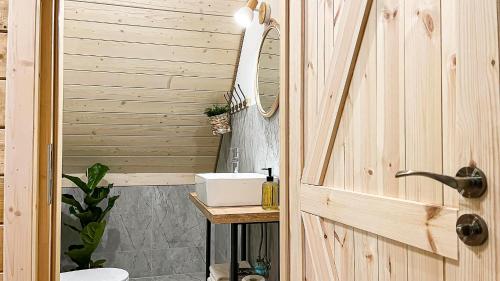 uma casa de banho em madeira com um lavatório e um espelho em ZaBieszczaduj - apartamenty do wynajęcia em Lutowiska