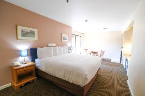 a bedroom with a large white bed and a table at Aspinquid Resort in Ogunquit