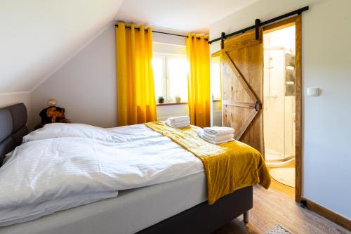 a bedroom with a bed with yellow curtains and a window at Odpoczywajka in Borucino