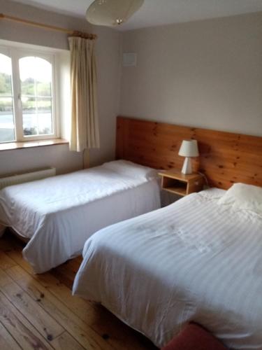 two beds in a hotel room with a window at Parnell house in Ennis