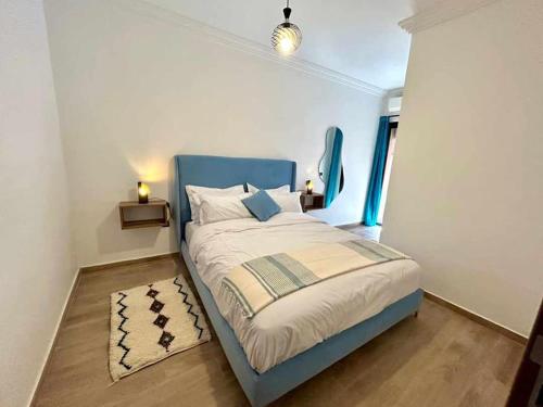 a bedroom with a bed with a blue headboard and a rug at Appartement Annakhil in Rabat