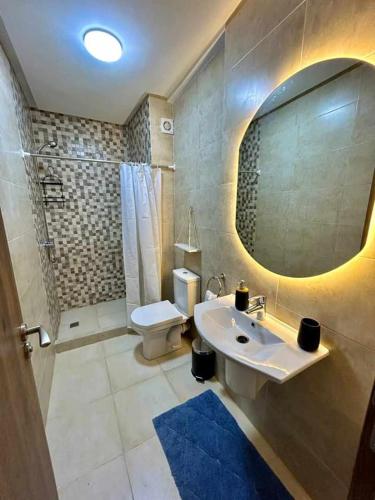 a bathroom with a sink and a toilet and a mirror at Appartement Annakhil in Rabat