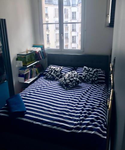 - un lit avec des draps et des oreillers à rayures bleus et blancs dans l'établissement Bel appartement à Paris, à Paris