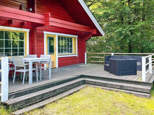 une maison rouge avec une table et des chaises sur une terrasse dans l'établissement 4 person holiday home in HJ RNARP, à Hjärnarp