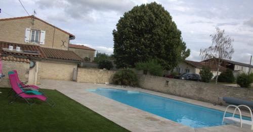 a swimming pool in a yard next to a house at Gites la Marquise in Prisse-la-Charriere