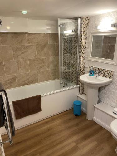 a bathroom with a tub and a sink at The Dairy-Petting Farm-Indoor Pool-Play Areas-Parkland-Woodland-Lake,Ponds&Stream-min2 night stay in Lechlade