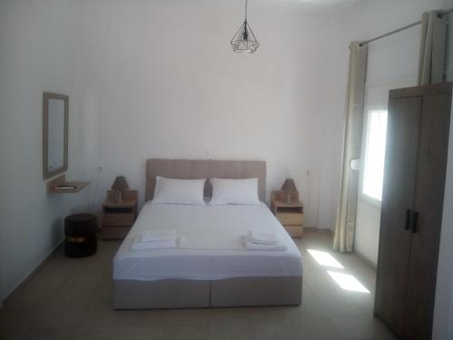 a bedroom with a white bed and a window at AMPELOS ANDROS in Batsi