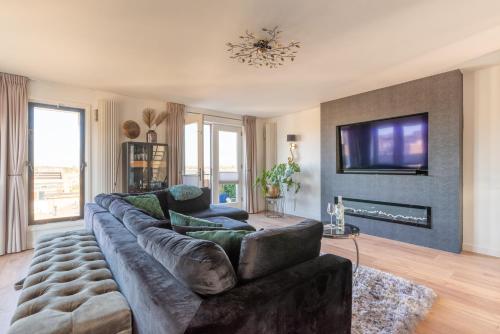 a living room with a large couch and a tv at Beach Villa & Studio in Zandvoort