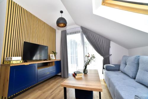 a living room with a blue couch and a tv at Za Górami in Wetlina