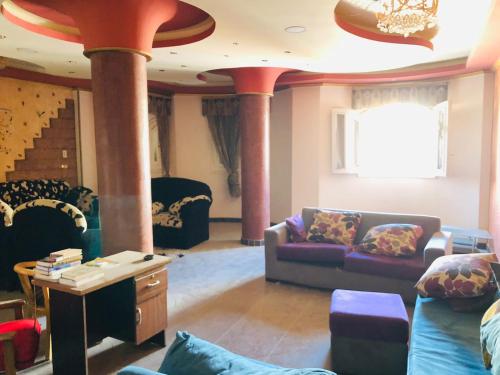 salon z kanapami, stołem i kolumnami w obiekcie شقة مفروشة w mieście Al-Mansura