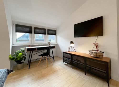ein Wohnzimmer mit einem Schreibtisch und einem Computer an der Wand in der Unterkunft Komfortable und gemütliche Wohnung mit 2 SZ in Mönchengladbach