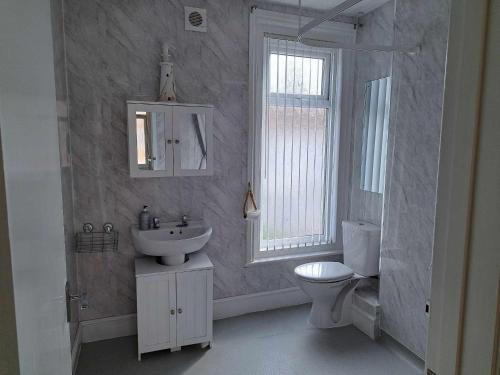 a white bathroom with a sink and a toilet at Immaculate 2-Bed Cottage - Free WiFi in Bridlington