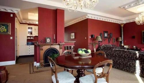 a living room with red walls and a table and a couch at Te Aroha维多利亚度假屋 in Te Aroha