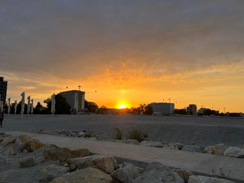 a sunset on a beach with buildings and rocks at Blue Luxury Apartment Lake On in Mamaia
