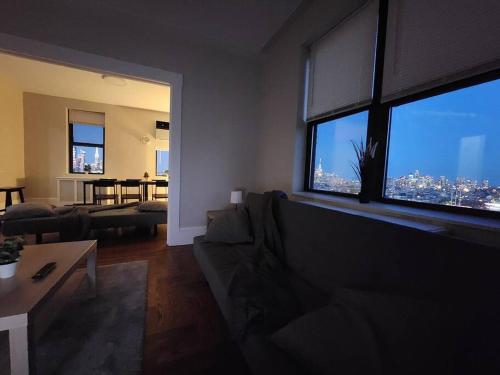 ein Wohnzimmer mit einem Sofa und einem großen Fenster in der Unterkunft Elegant 2 bed gem! mins from NYC in Union City