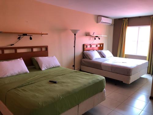 een slaapkamer met 2 bedden en een raam bij 101 Suites in Paramaribo