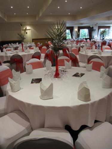 a banquet hall with white tables and red chairs at Weston Hall Hotel Sure Hotel Collection by Best Western in Bulkington