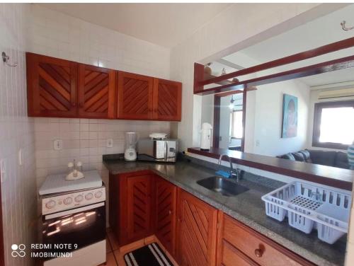 - une cuisine avec des placards en bois, un évier et une cuisinière dans l'établissement Condominio Villa Aurora, 150m da Praia de Taperapuam!, à Porto Seguro
