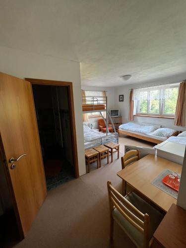 a room with two beds and a table and a dining room at Penzion Za potokem in Nová Pec