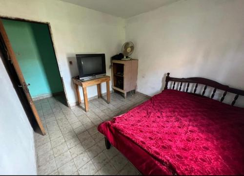 1 dormitorio con cama roja y TV de pantalla plana en La roka gym casa, en San Salvador de Jujuy