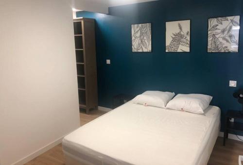 um quarto com uma cama branca e uma parede azul em Gîte du centre- Maison avec extérieur en centre ville em Mèze