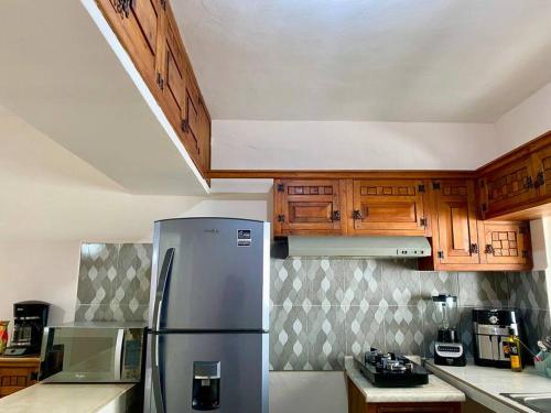 a kitchen with a stainless steel refrigerator and wooden cabinets at Casa María.-Casa completa in Cozumel