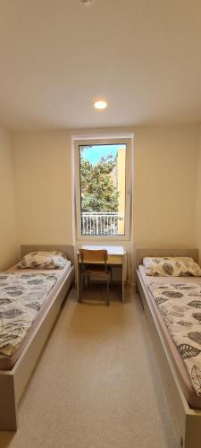 two beds in a room with a window at Zagreb budget rooms in Zagreb