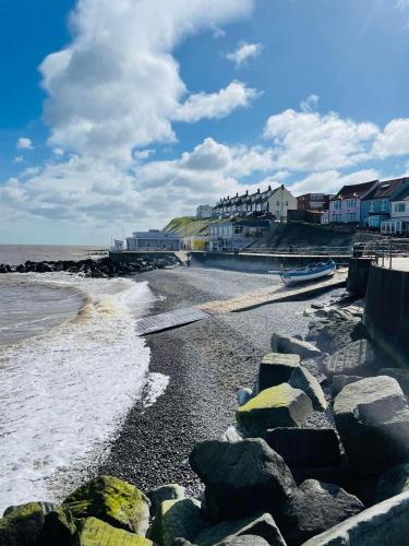 a beach with rocks and houses and the ocean at Fishermans Flint cottage in Sheringham