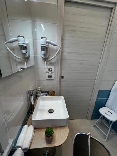 La salle de bains est pourvue d'un lavabo blanc et d'une chaise. dans l'établissement B&B VIRGILIO LAMEZIA AIRPORT, à SantʼEufemia Lamezia