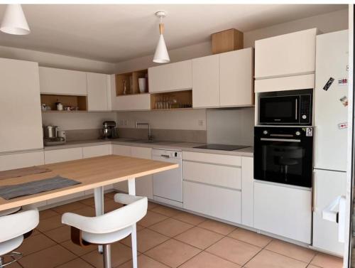eine Küche mit weißen Schränken und einem Holztisch in der Unterkunft Maison à Chiberta, à 5 minutes à pieds des plages in Anglet