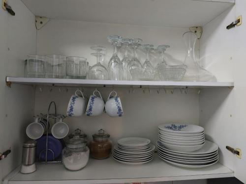 a shelf filled with plates and glasses and utensils at Guest House GAAM Las Condes in Santiago