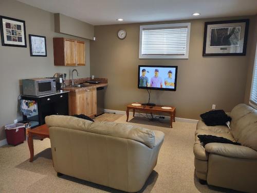 a living room with two couches and a flat screen tv at Spacious One Bedroom Walkout Basement Suite in Calgary