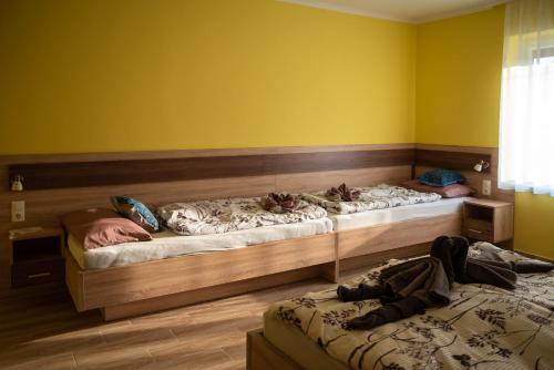 two beds in a room with yellow walls at Benige vendégház in Demjén