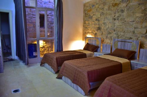 a room with three beds and a stone wall at Dana View Guest House in Dana