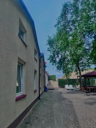 a brick sidewalk next to a building with a tree at Gościniec rybacki in Dąbki