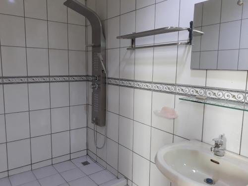 een wit betegelde badkamer met een wastafel en een spiegel bij Beido Qixing in Beidou