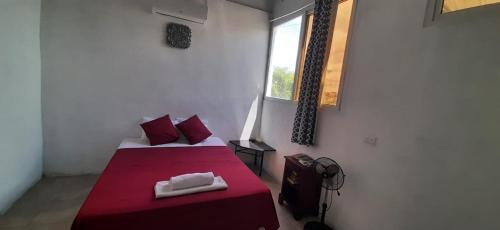 1 dormitorio con 2 camas con sábanas rojas y ventana en Casa Zoila Hospedaje frente al lago Lakefront lodging, en Flores